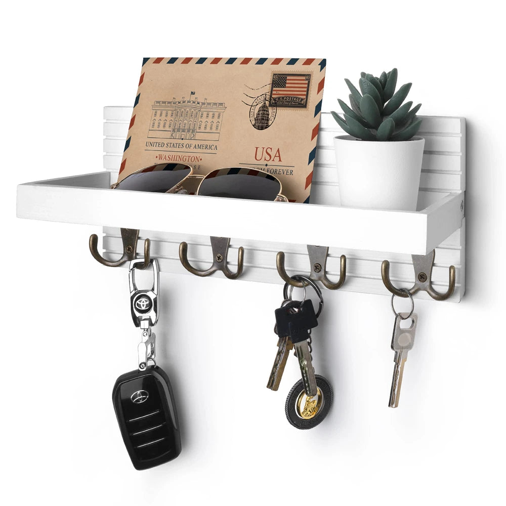 Wall-mounted key holder with hooks holding keys, a car key fob, and a plant on a white background.