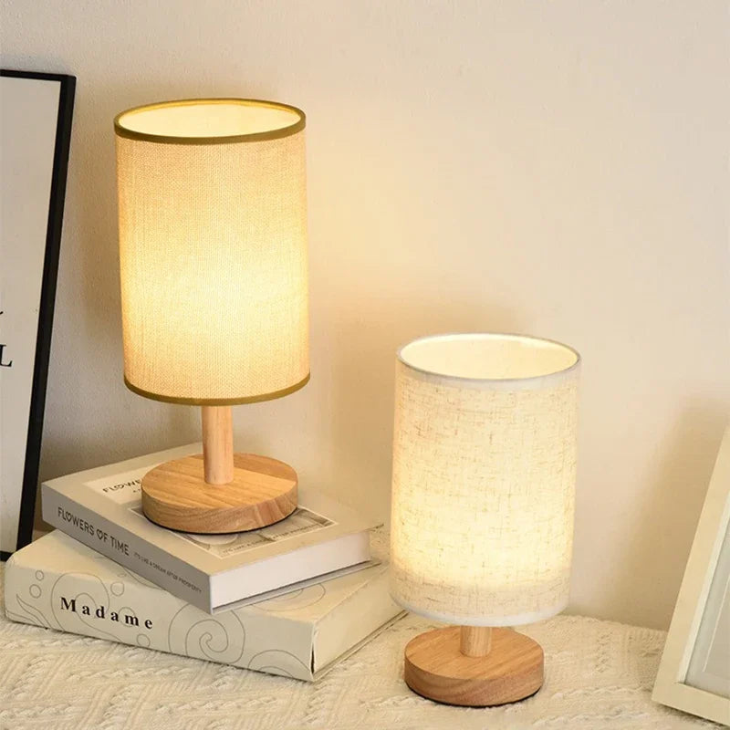 Two small table lamps with wooden bases on a surface.