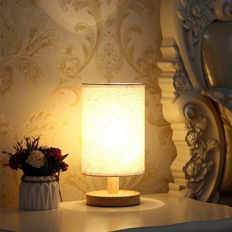 Decorative table lamp with floral arrangement on a surface with ornate wall paper.
