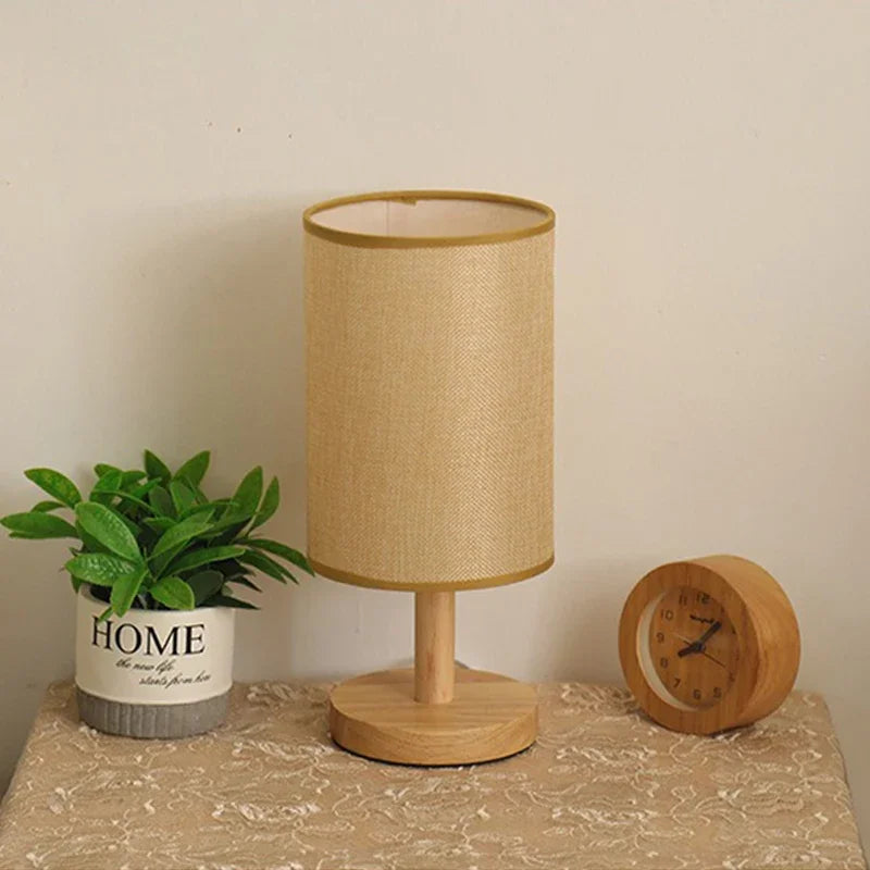 Table lamp with a plant and clock on a surface against a beige wall